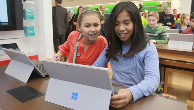 Two girls work on Surface devices in a workshop