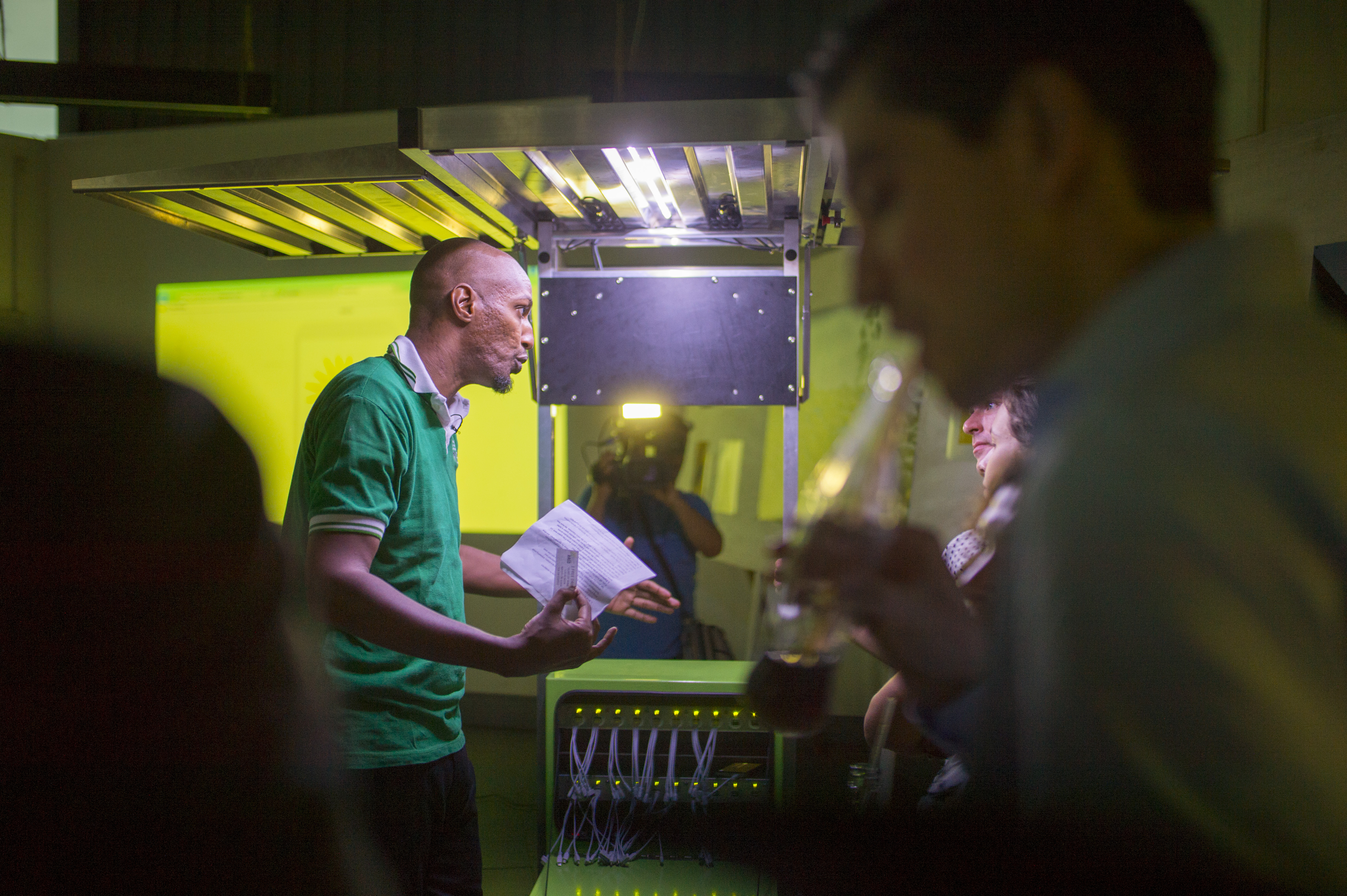 Photo of an African Renewable Energy Distributor employee explaining how a mobile solar kiosk hub works