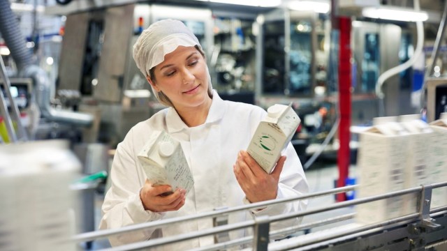 Tetra Pak worker checking milk cartons on production line