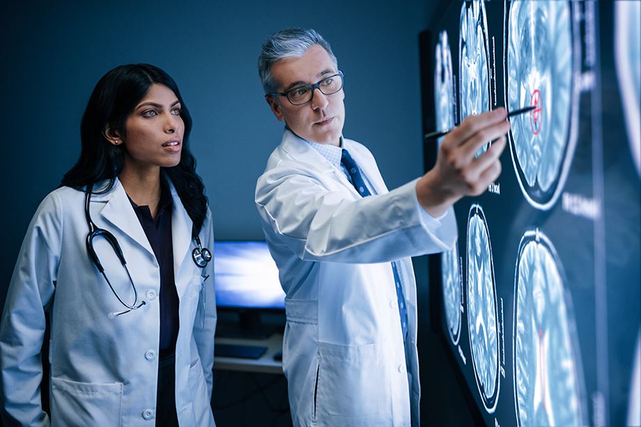Two doctors look over brain scans in a clinical setting