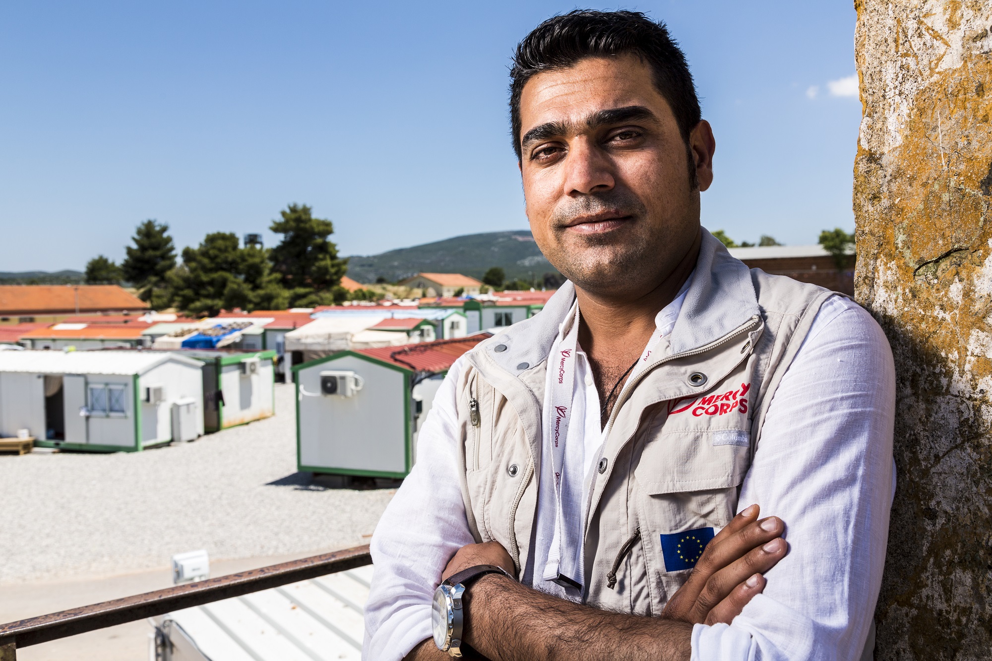 Former refugee and Mercy Corps worker Farhad Agajan poses with arms crossed at a refugee camp in Greece