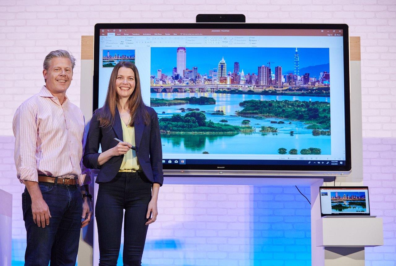 Nick Parker and Roanne Sones stand on stage with the 70" Windows Collaboration Display from Sharp