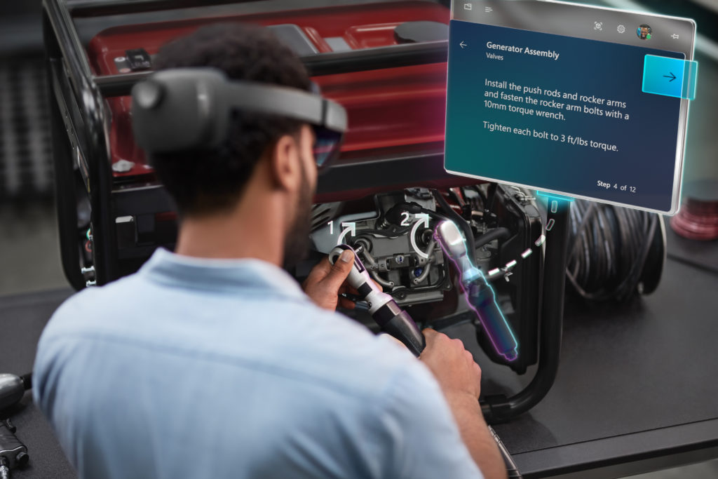Man wearing HoloLens 2 consults a hologram of a guide as he works on machinery