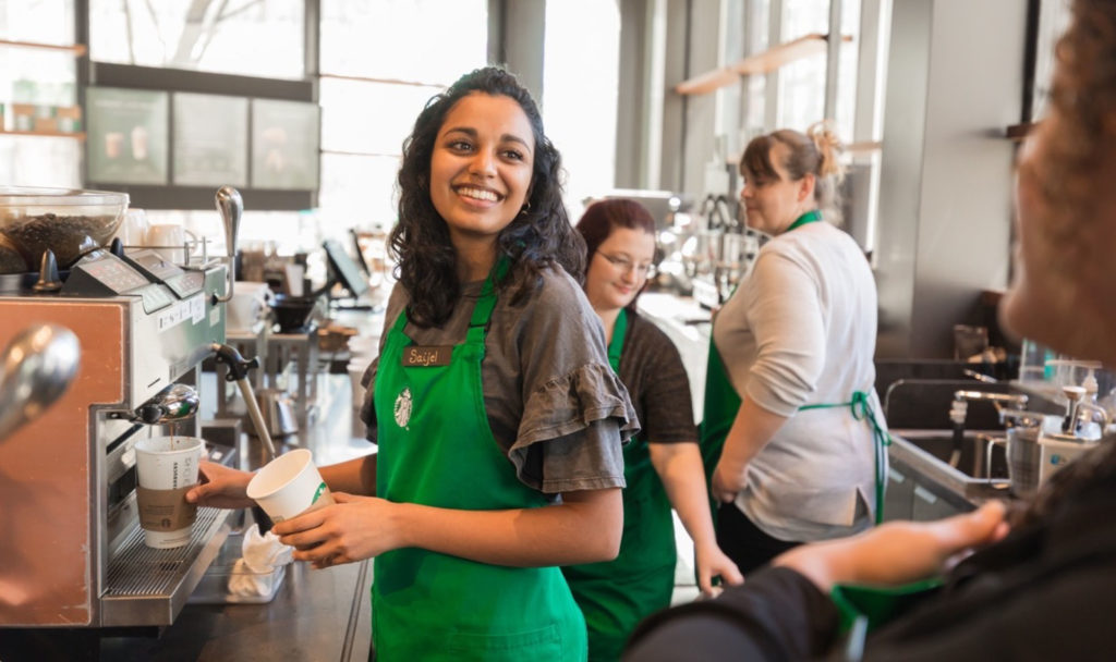 Photo of Starbucks barista smiling and making an espresso drink