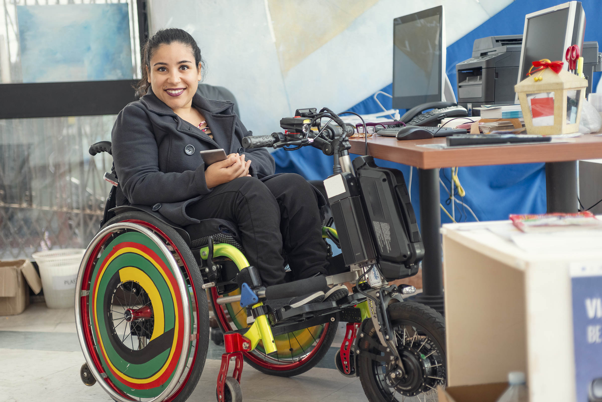 Woman in colorful wheelchair at computer desk