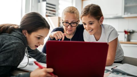 Two girls and woman looking at laptop screen