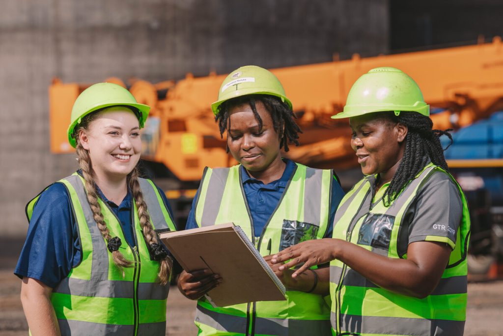 women in hard hats and vests discussing work