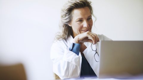 Female medical worker looks at laptop