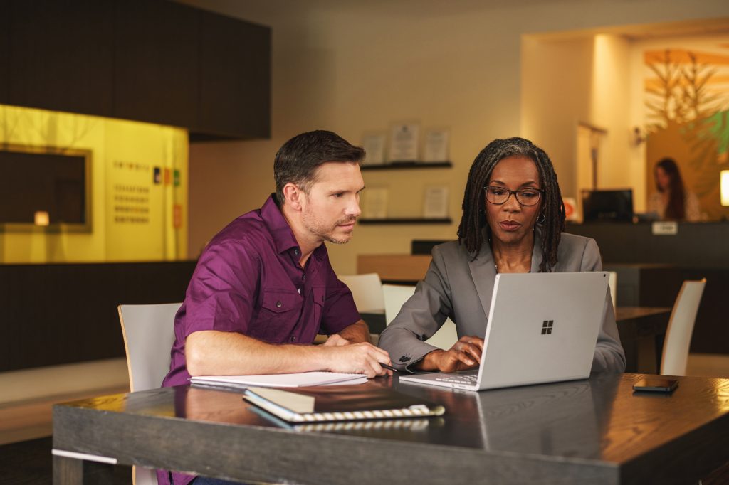 Male and female coworkers look at laptop