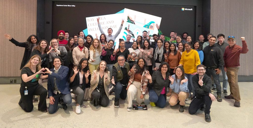 About 40 Microsoft employees smiling in front of a screen that says Bay Area Culture and Inclusion Day.