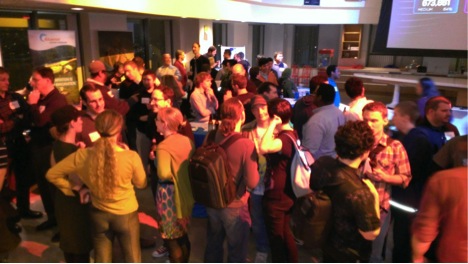 Students and Developers mingle in front of Dance Central 3 on the big screen.