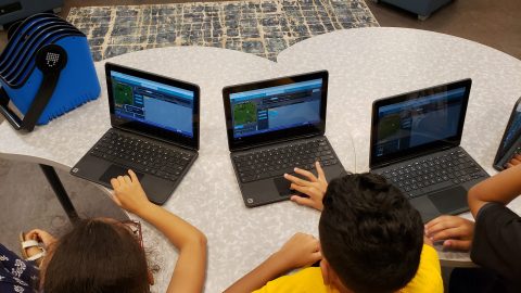Students grouped around Surface laptops experience a Minecraft Hour of Code.