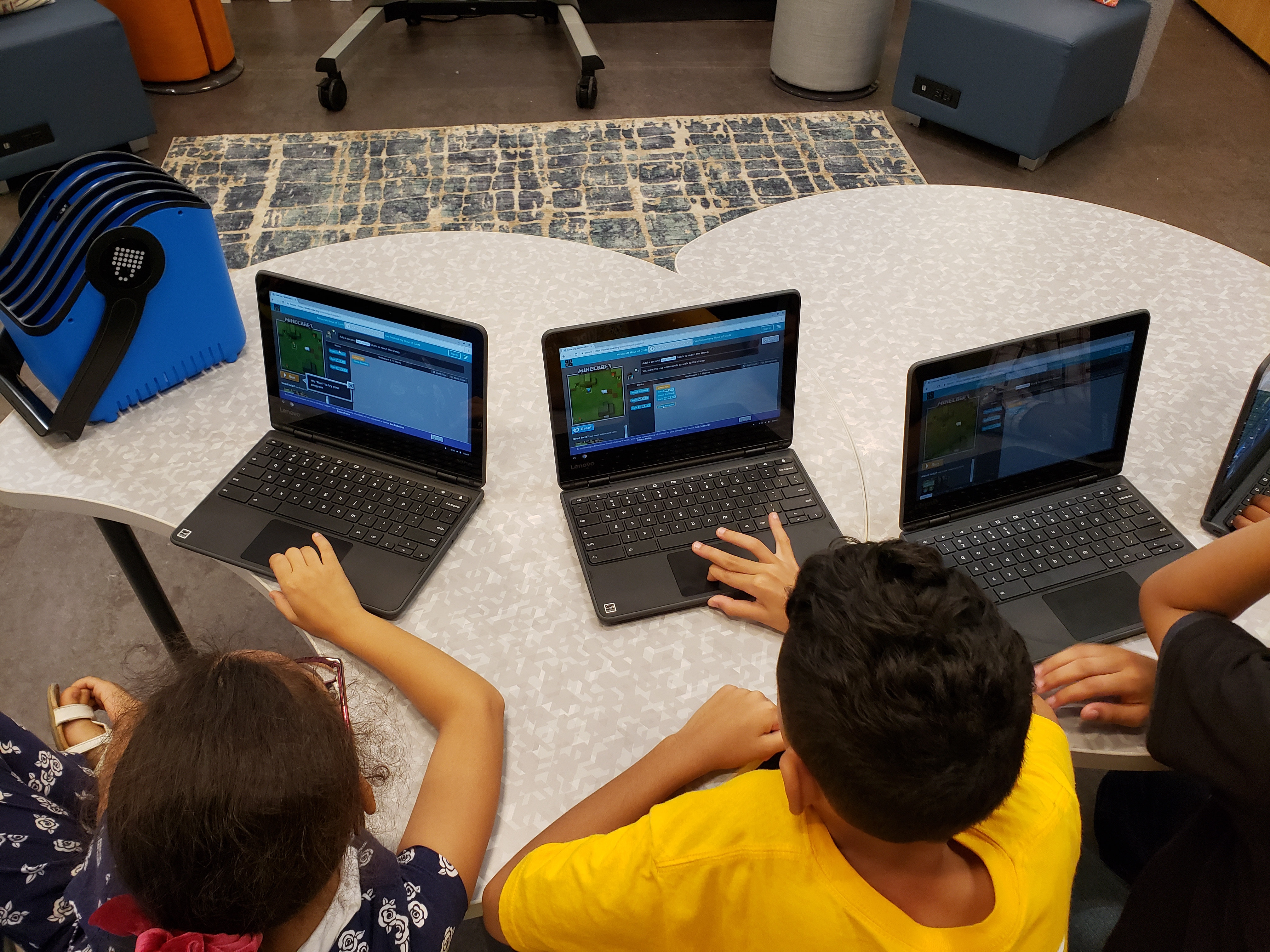 Students grouped around Surface laptops experience a Minecraft Hour of Code.