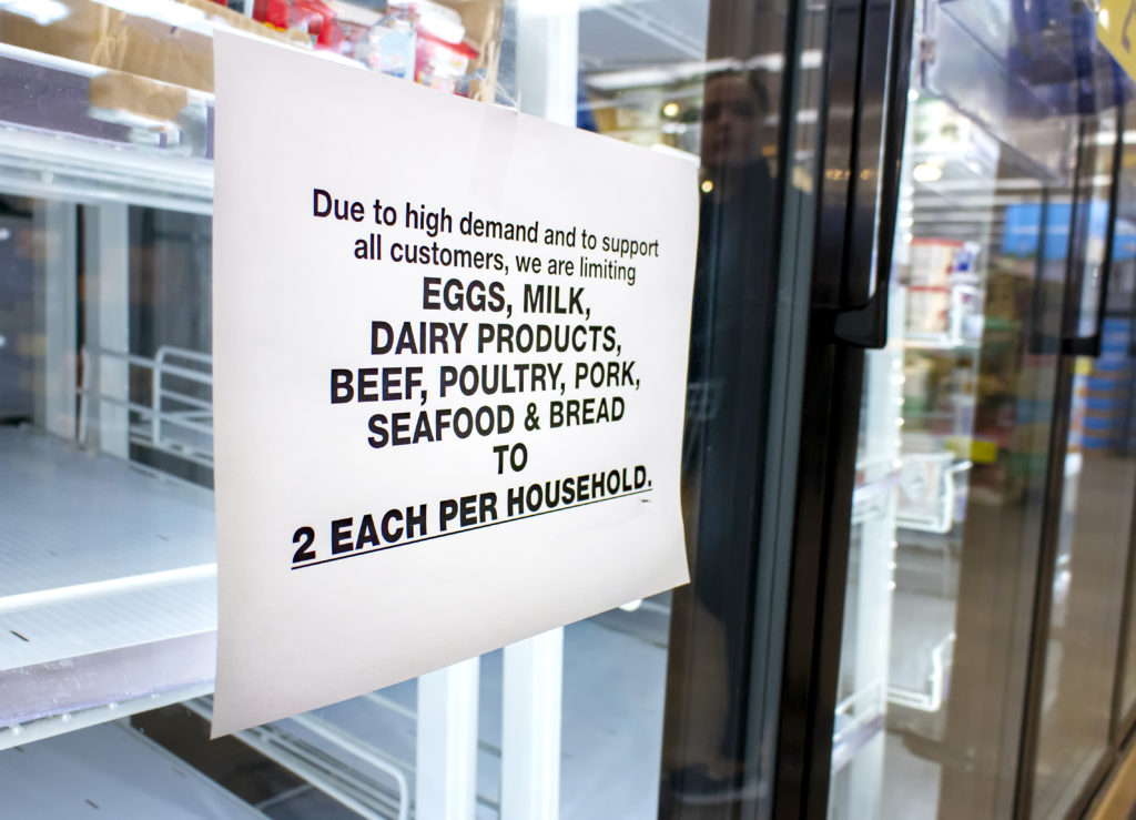 Coronavirus related sign rationing food such as dairy products ,meat,seafood,bread and eggs at a supermarket. The shelves of the cooler are fairly empty