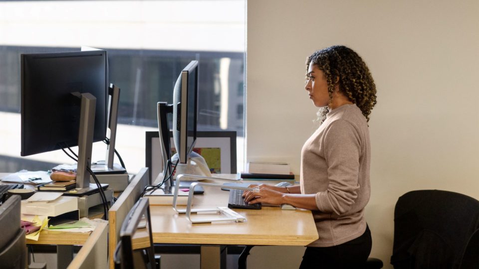 A woman works at a standing desk