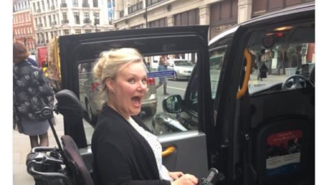Jessica is looking excited while entering a wheelchair accessible taxi!