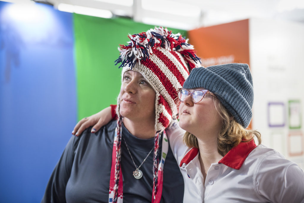 Two women wearing red, white and blue hats with their arms around each other.