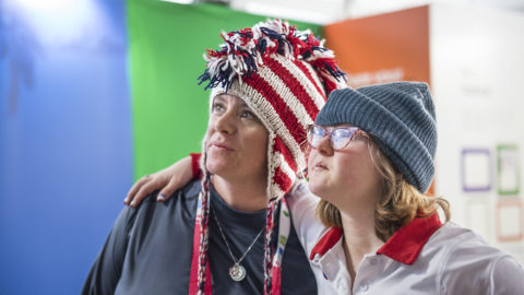 Two women wearing red, white and blue hats with their arms around each other.
