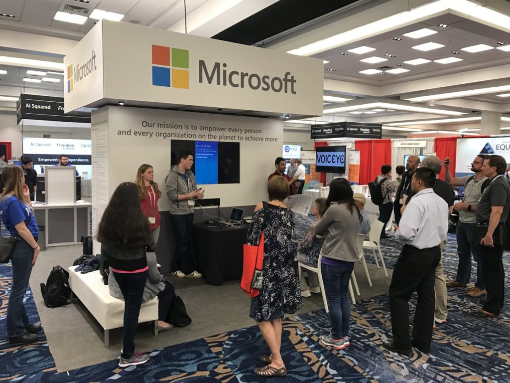 Group standing at a booth with a sign that says Microsoft.
