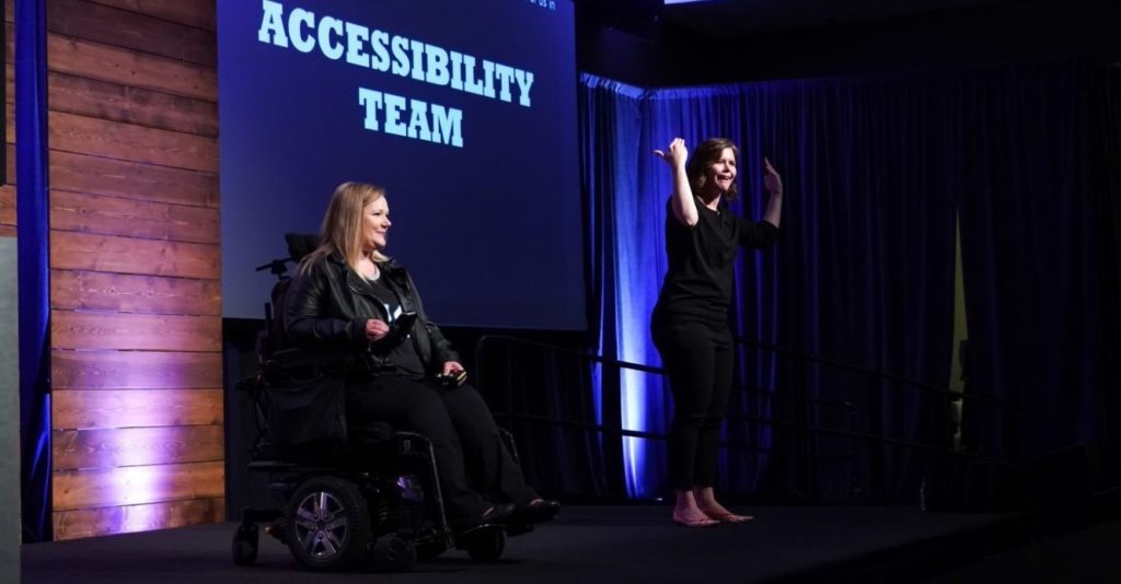 Jessica Rafuse presenting on stage at the 2019 Ability Summit. A sign language interpreter signs next to her.