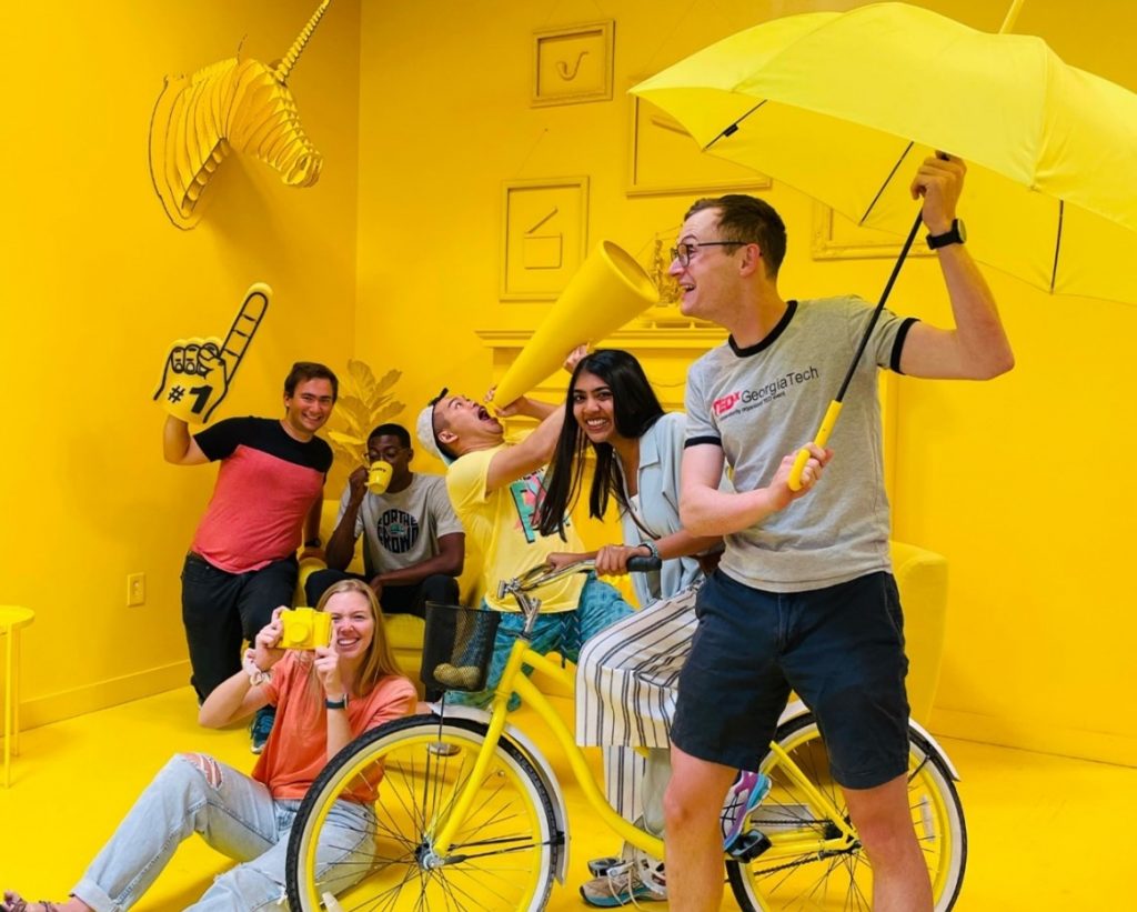 An image of the Mentra team in a yellow room holding umbrellas