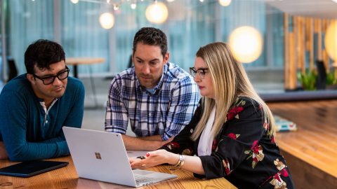 A group of tech workers hold meeting in common space of U.S. office.