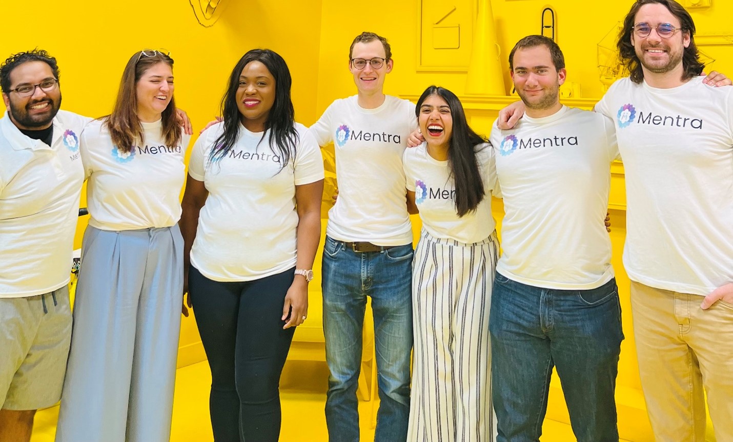 7 of the Mentra team members in a yellow colorful room smiling 