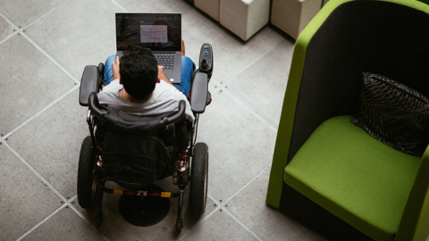 A man in a wheelchair works on his laptop