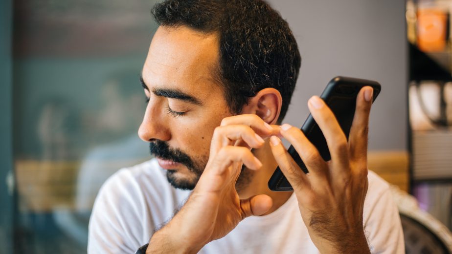 A man holds a phone near his ear with his eyes closed.