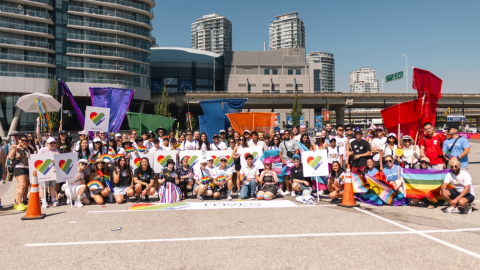 100 Tech Loves Pride marchers pose and cheer together for a celebratory group photo after completing the 2014 Vancouver Pride Parade route.