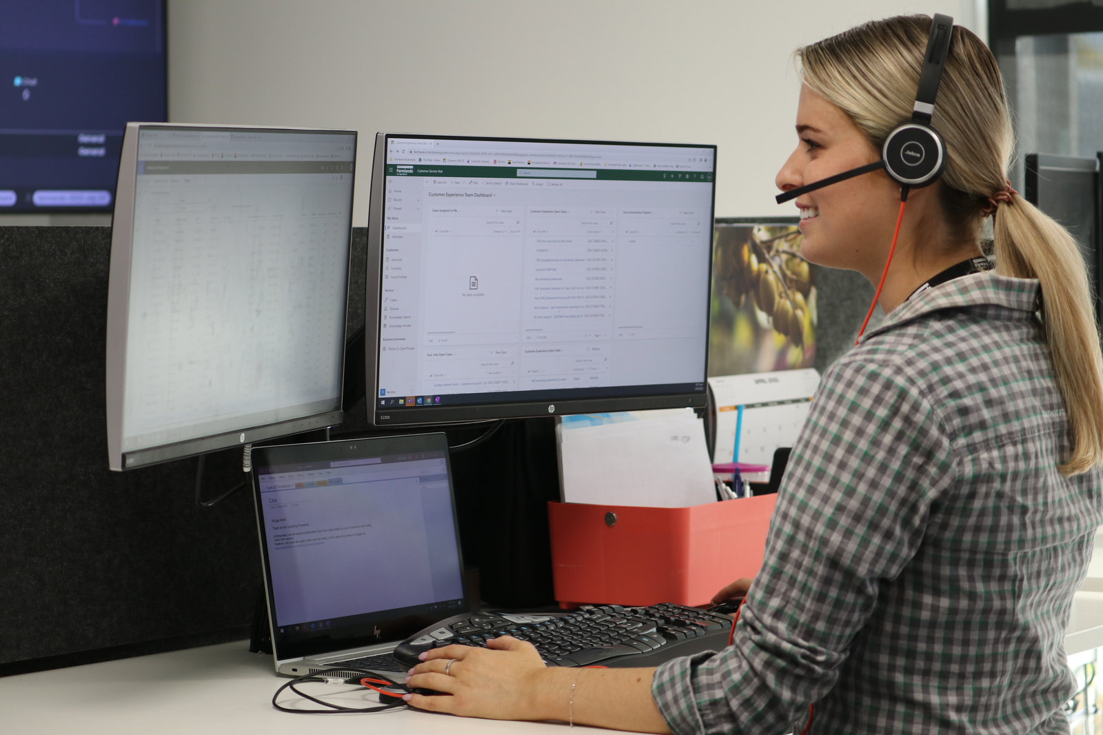 Customer service agent for Farmlands looking at two screens and working on a laptop