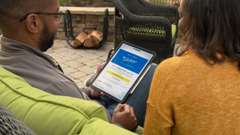 Two people looking at CarMax on a device.