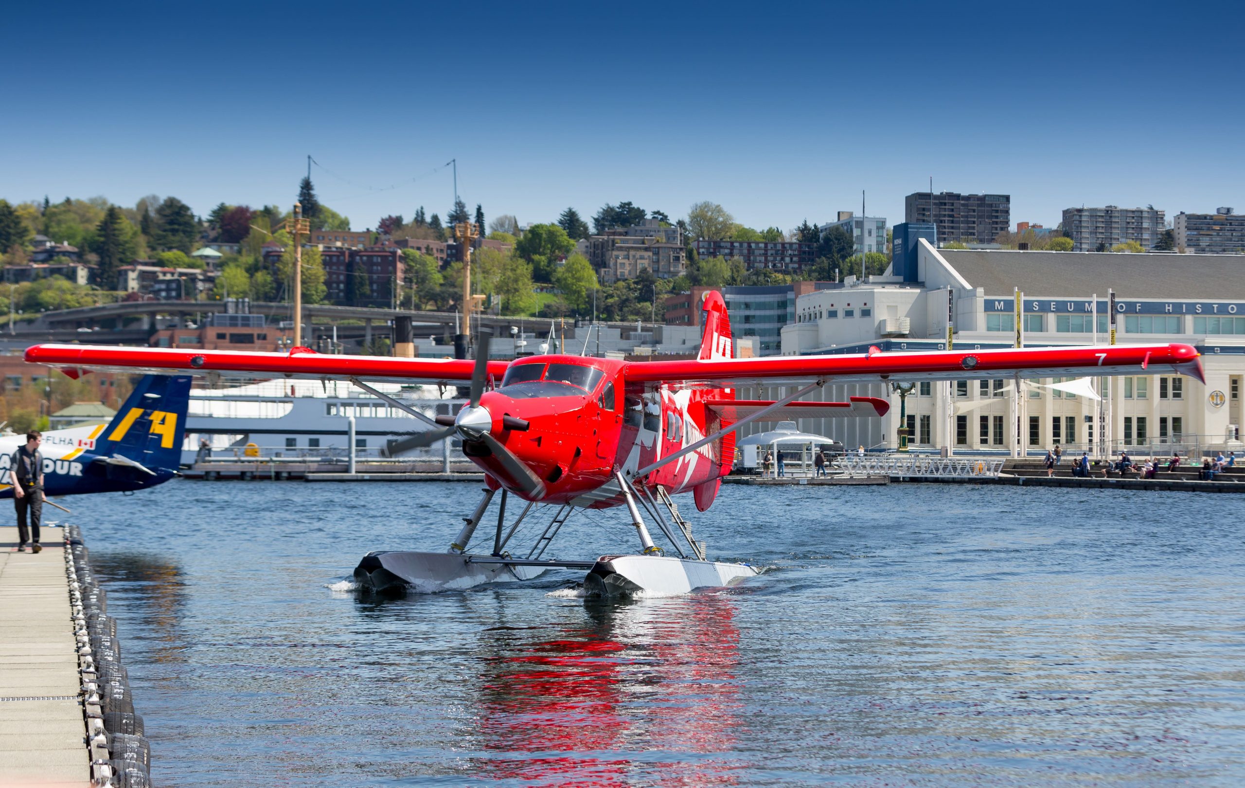 Photo of a bright red seaplane on the water next to a dock