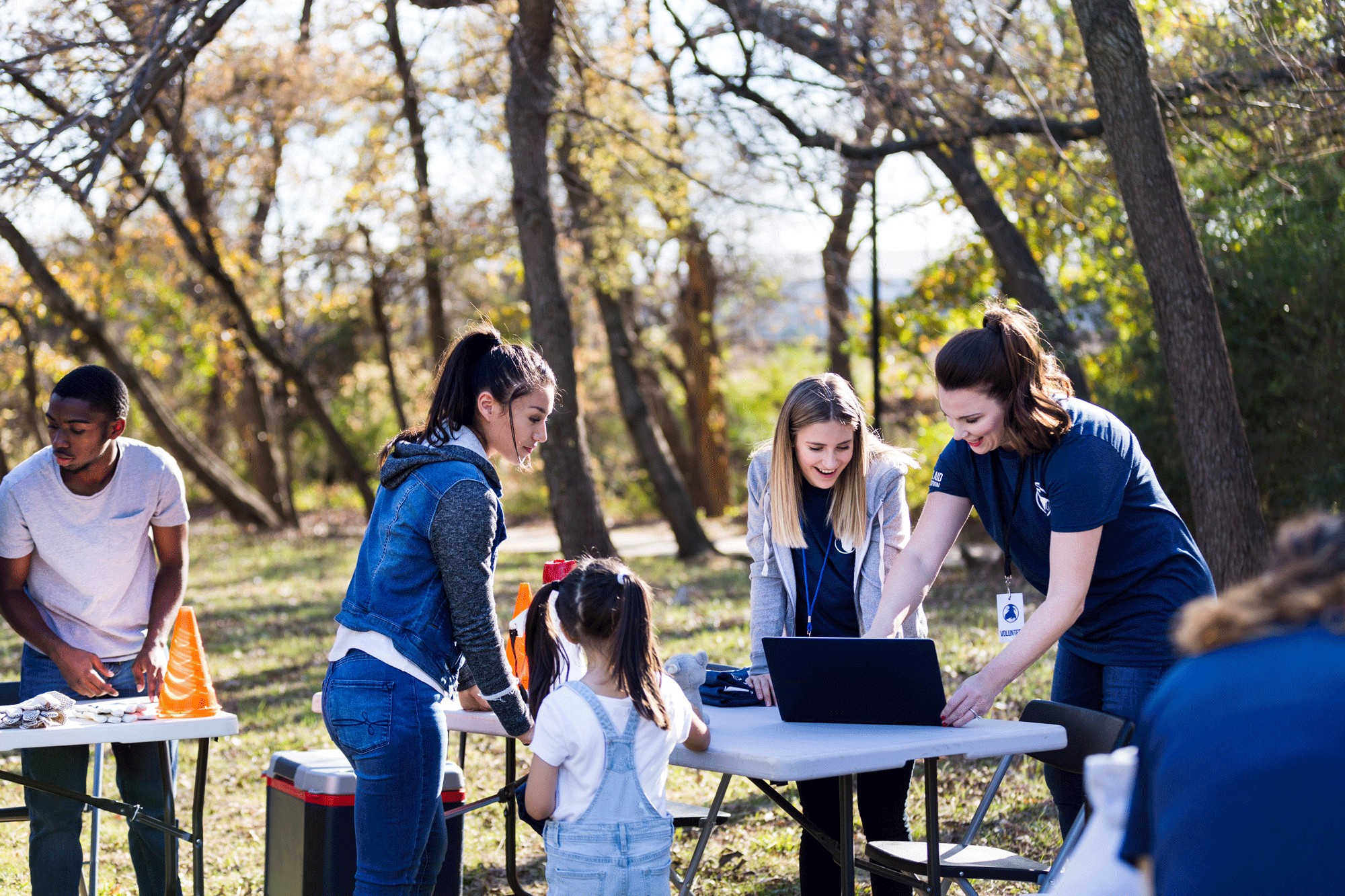 a group of adults and children using a laptop in a park
