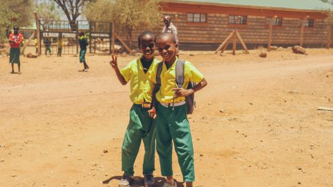 Two primary school kids in front of a school in Africa
