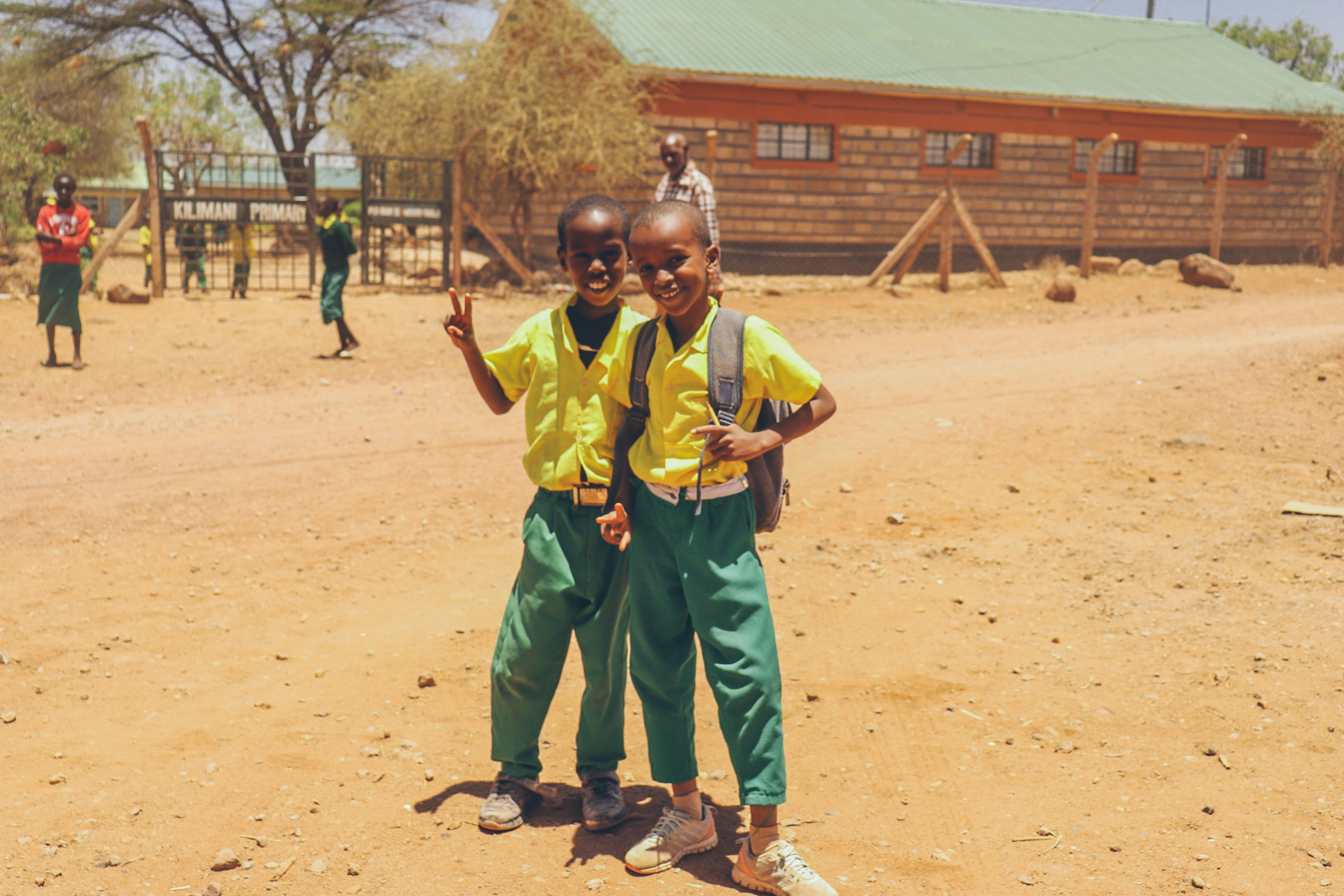 Two primary school kids in front of a school in Africa