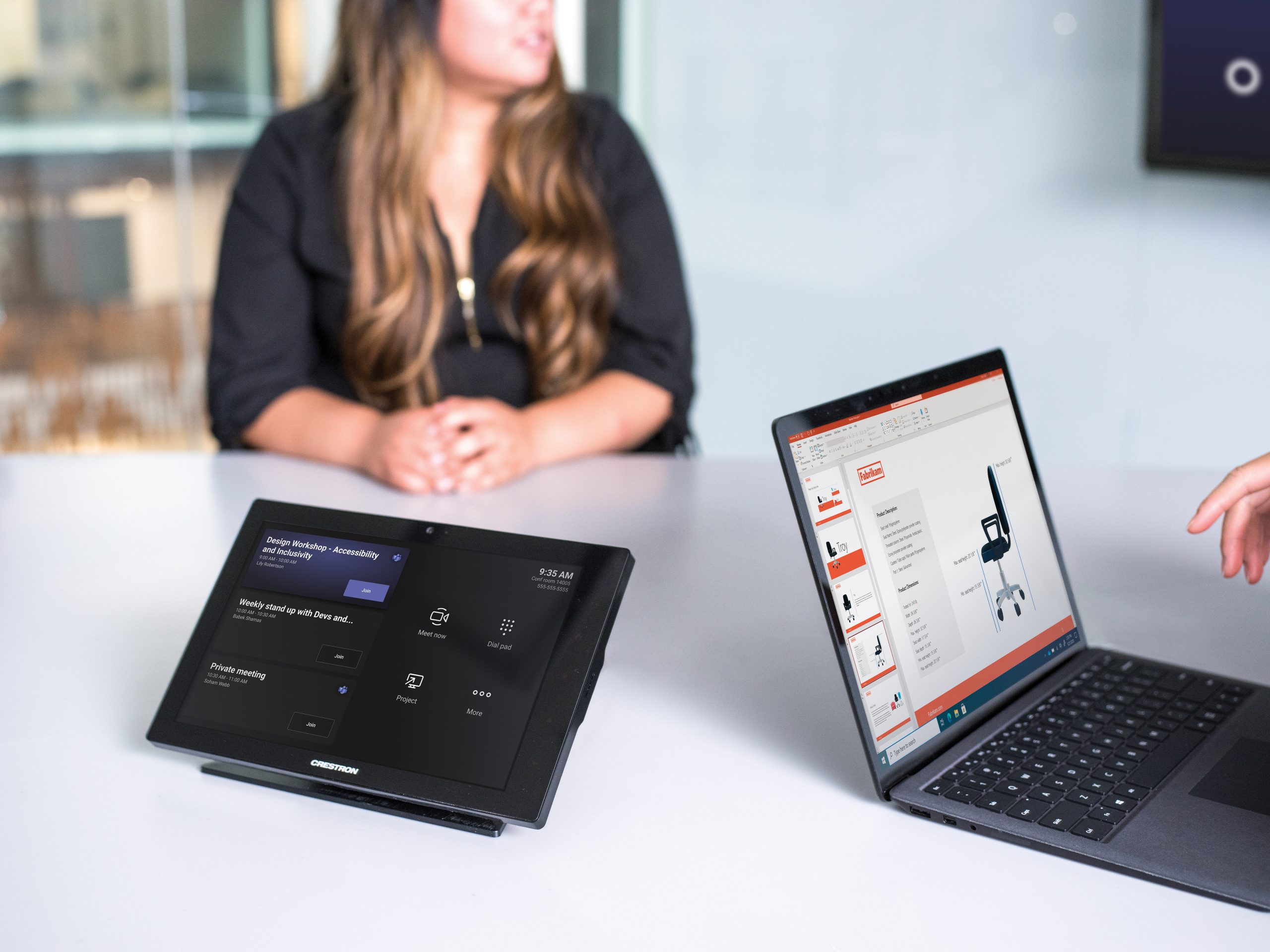 One female in a conference room with a Crestron Teams Rooms touch console with the Microsoft Teams pre-meeting screen showing with a Surface in view.
