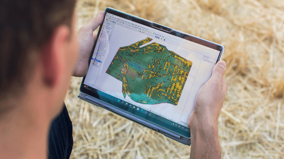 a farmer uses a tablet to analyze his land