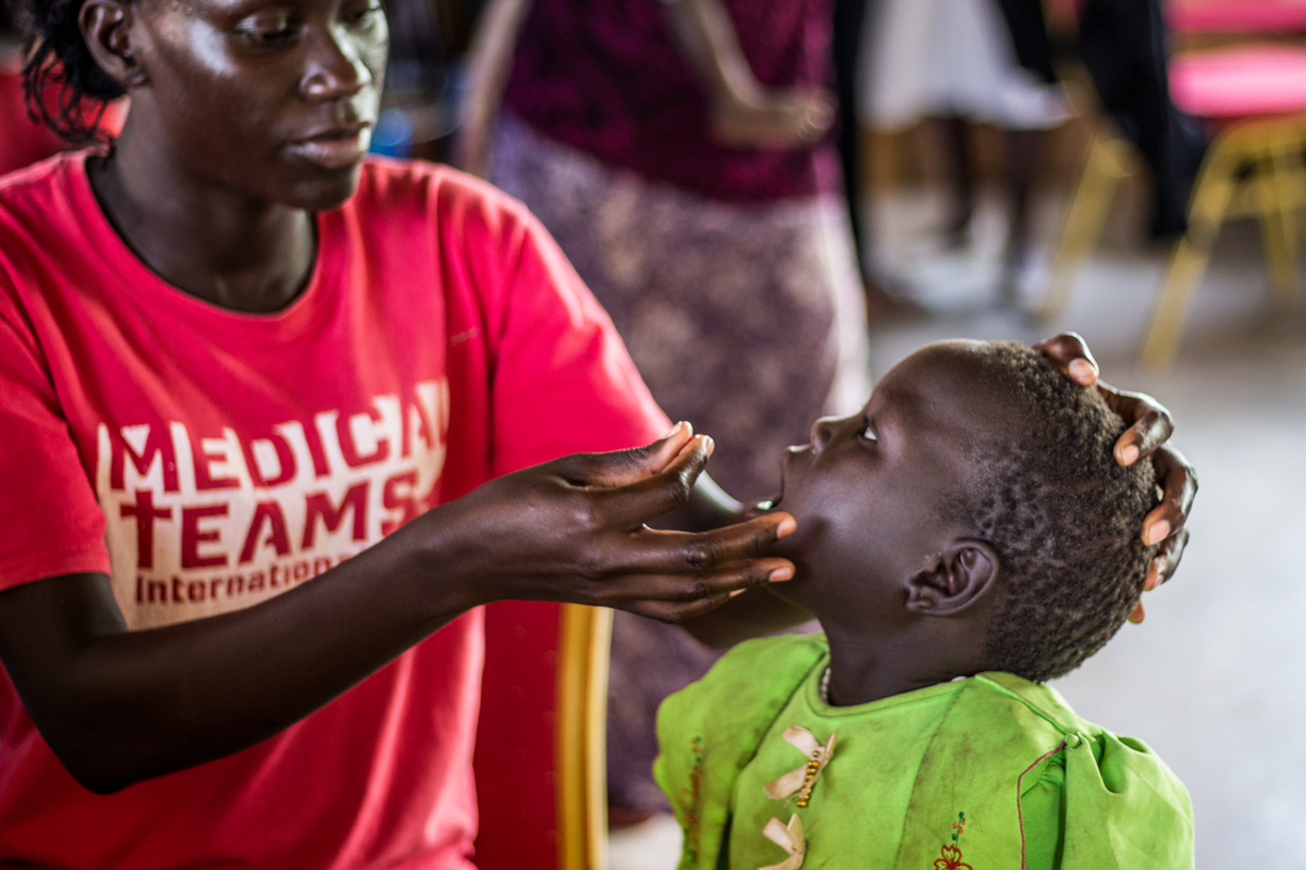 Medical Teams International worker checks a little girl's throat