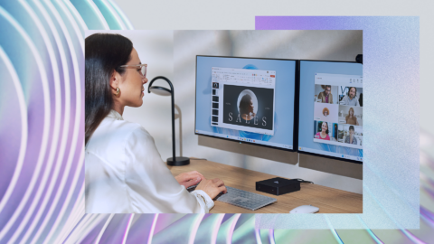 Person working at a desk with two computer monitors. The left screen displays a presentation titled 'SAFES' with an image of a planet or moon. The right screen shows a video conference with multiple participants in small windows.
