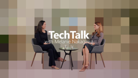 The image features Melanie Nagawaka and Nanna -Louise seated facing each other with a small round table between them. The background is pixelated. Text reads: 'TechTalk with Melanie Nakagawa'.